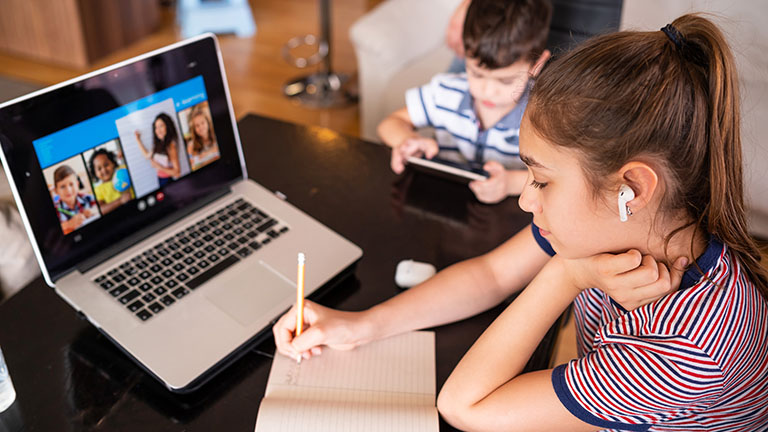 Teenage girl studying with video online lesson at home family in isolation Homeschooling and distance learning School children participating in online classes using a laptop