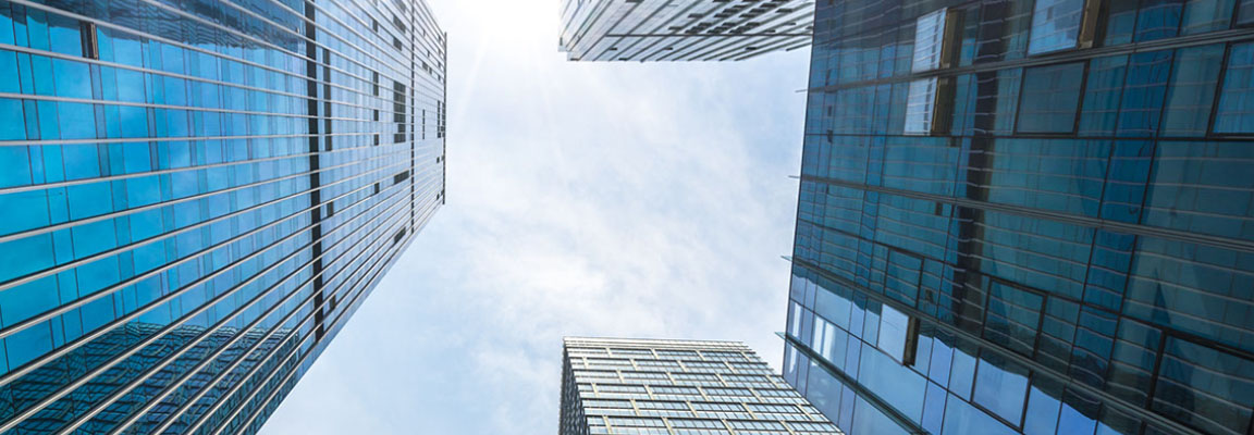 Looking up toward the sky and surrounded by four skyscraper buildings